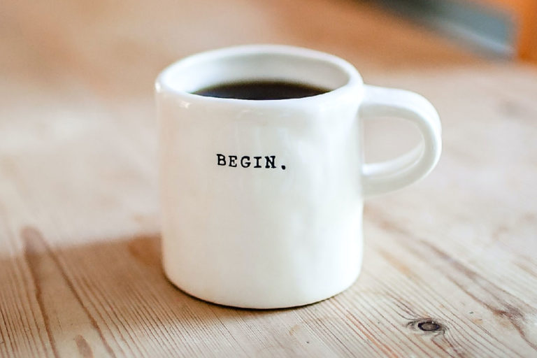 Coffee mug with the word "Begin" and coffee inside.
