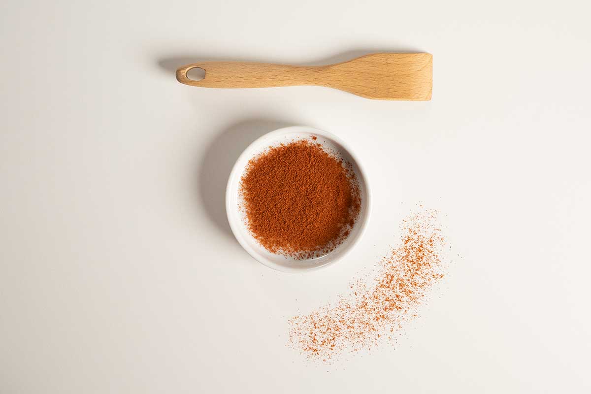 Cayenne in a white bowl with a wooden spoon over it.