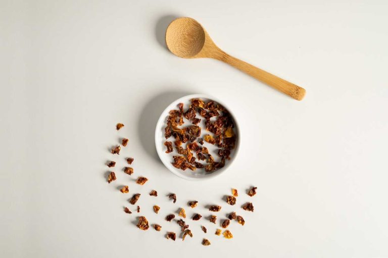 Dehydrated tomato flakes with a wooden spoon over the right hand side.