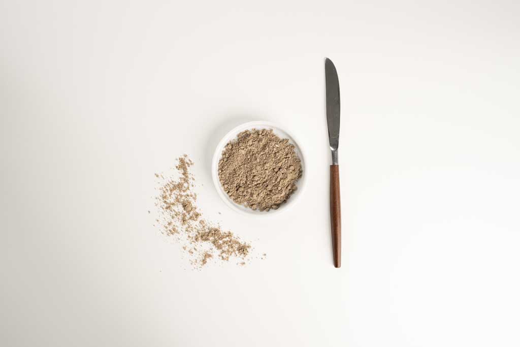 A bowl of chia protein powder with a butter knife next to it.