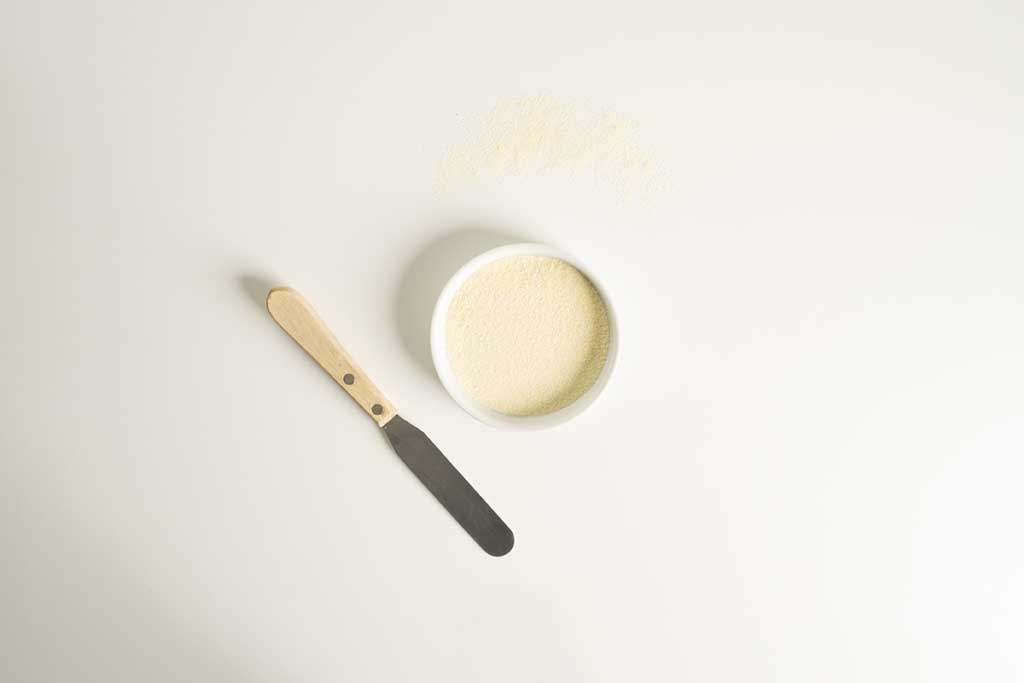 Potato Flour in small white bowl with a spatula next to it,
