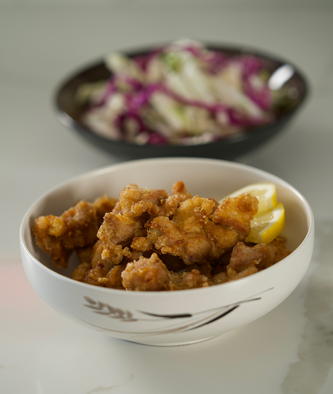 Bowl filled with Japanese Popcorn Chicken in front of a bowl of Asian Slaw