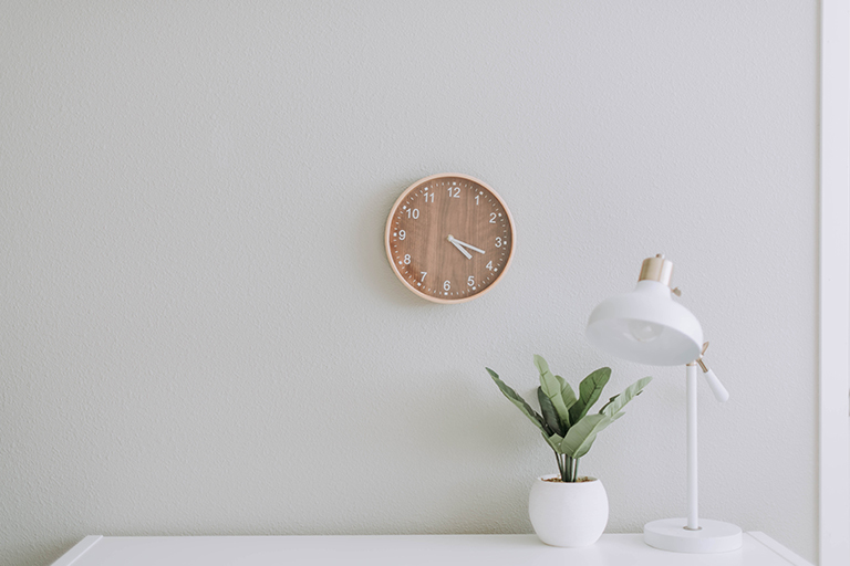Brown clock with a plant and a table lamp.
