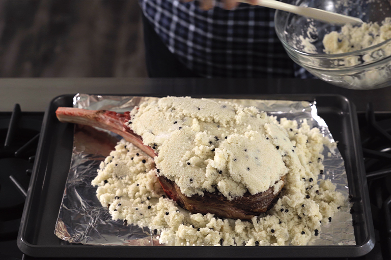 Tomahawk steak covered in salt and pepper mix