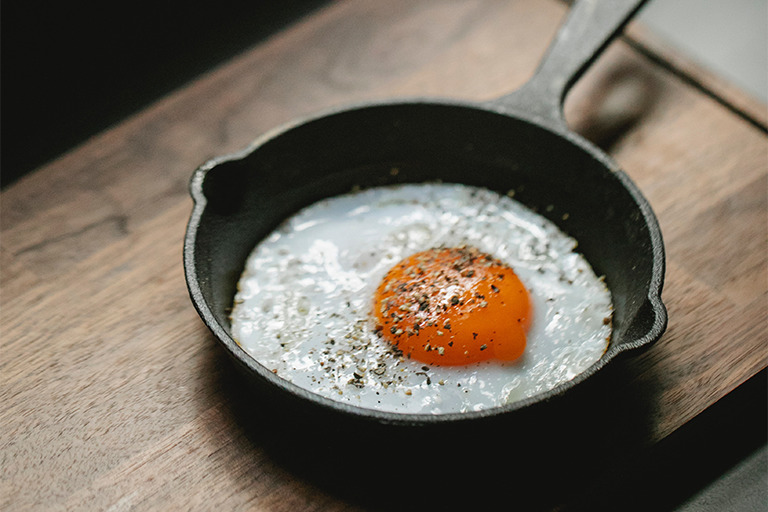An egg cooked in a small skillet with black pepper.