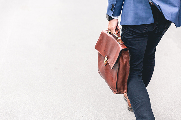 Professional working man walking with a brown leather briefcase.