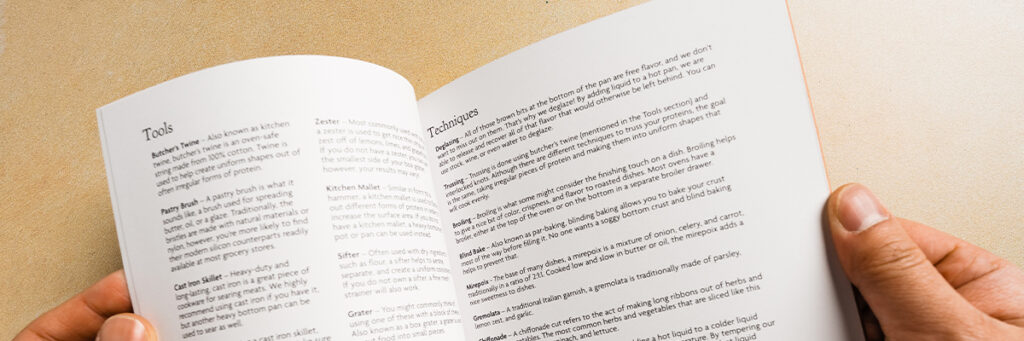 hands holding a book open to pages titled Tools and Techniques against a tan background