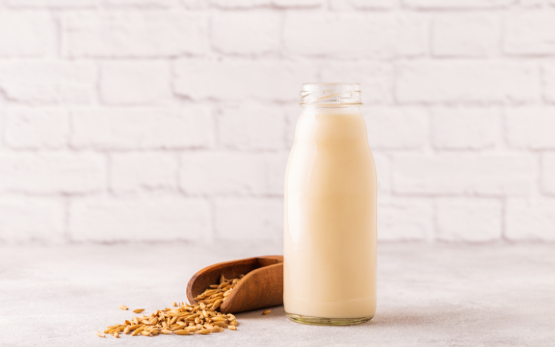 Oat ingredients - a jar of oat milk next to a container of oats spilled over.