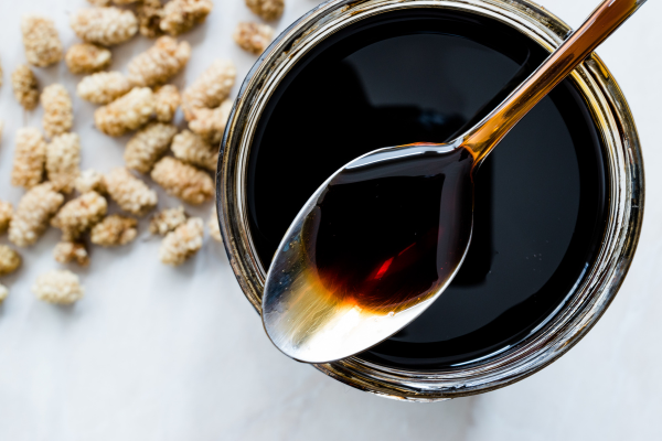 Spoon full of black molasses on top of a white counterpart.