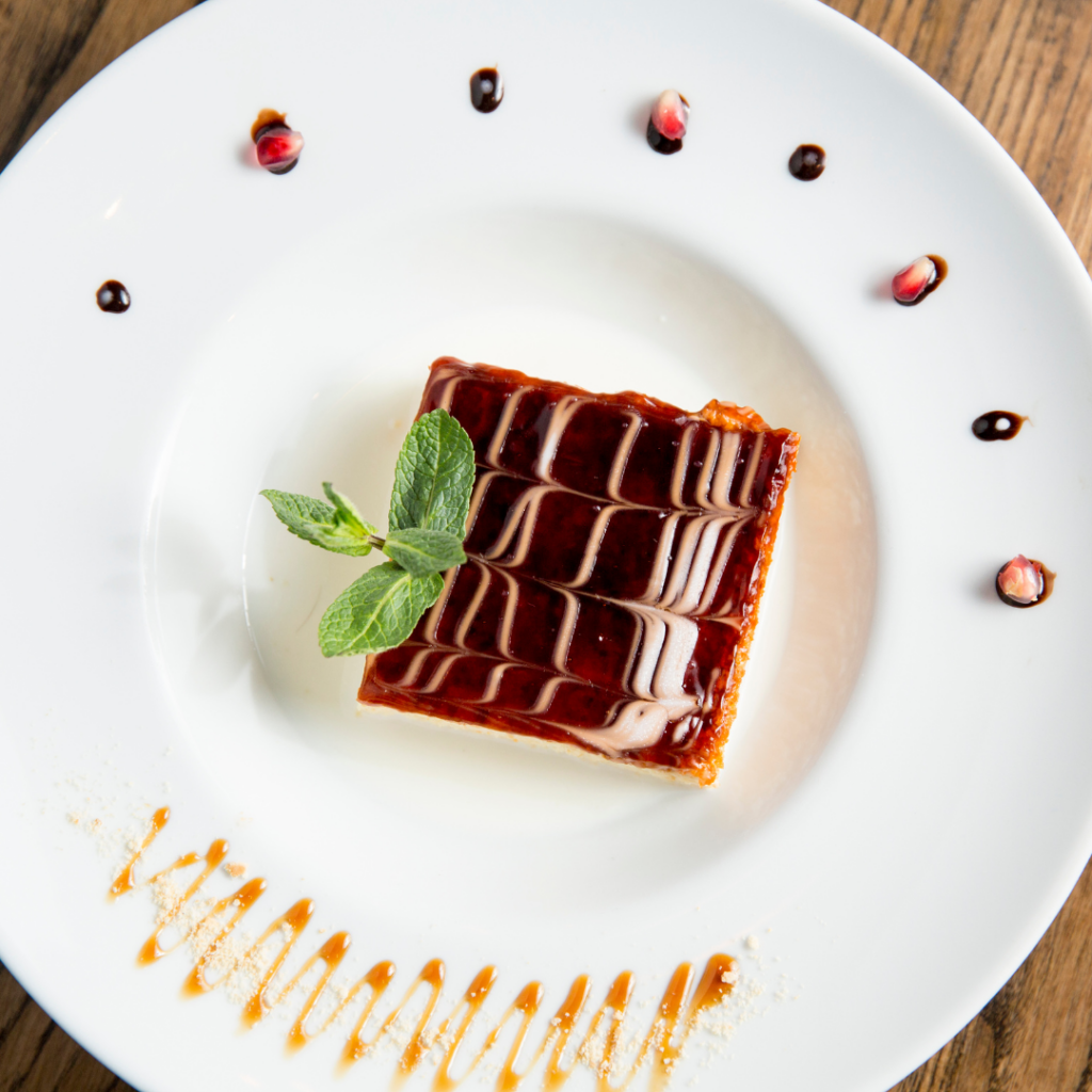 A slice of tres leches cake neatly decorated on a white plate.