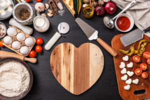 Valentine's Day emphasized through several ingredients scattered around a heart cutting board.