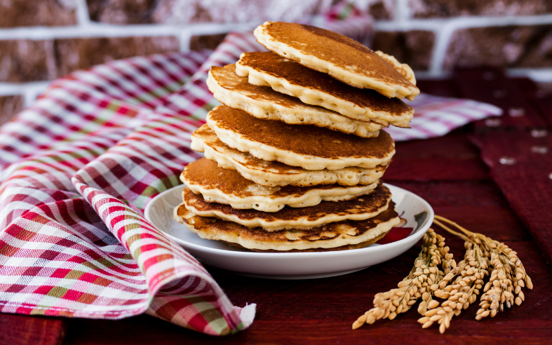 Brown rice flour pancakes stacked on top of one another, slightly tilting to the right at the top