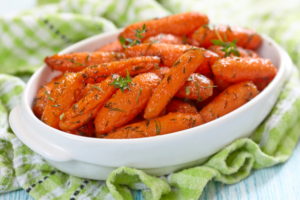 Brown sugar glazed carrots neatly stacked in a white bowl