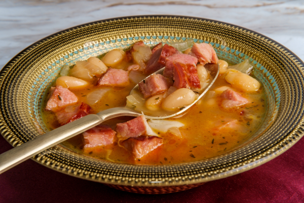 Navy Bean Soup on a countertop as a spoon is picking up a portion of it.