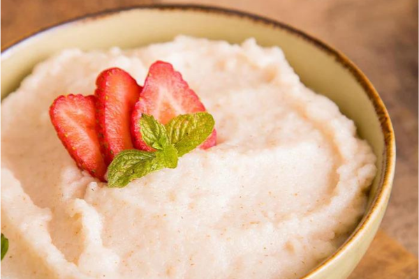 A photo of strawberry cream of wheat with sliced strawberries on top in a small bowl.