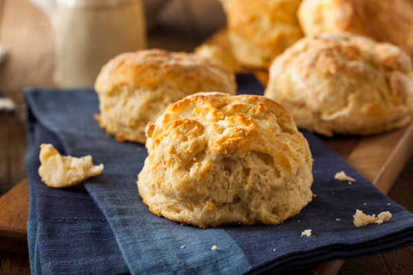 A photo of three biscuits sitting on a blue cloth on a wooden board.