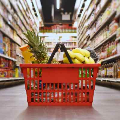 A photo of a basket full of food sitting in the middle of the grocery store isle.