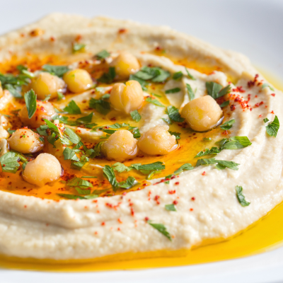 A photo of hummus topped with chickpeas and oil on a white plate.