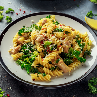 A picture of a bowl of pasta with greens and topped with cheese.