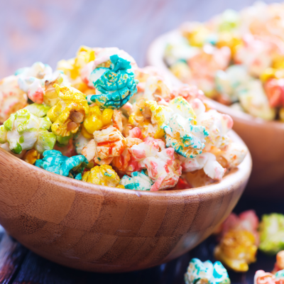 A photo of a wooden bowl full of colorful popcorn.