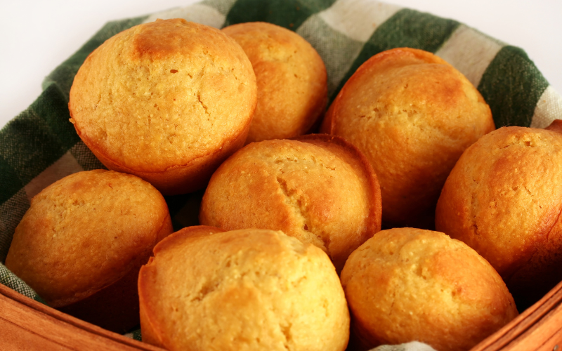 A photo of a basket filled with cornbread muffins.