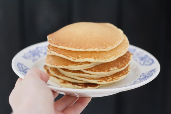 A stack of potato starch pancakes on a white plate that someone is holding.