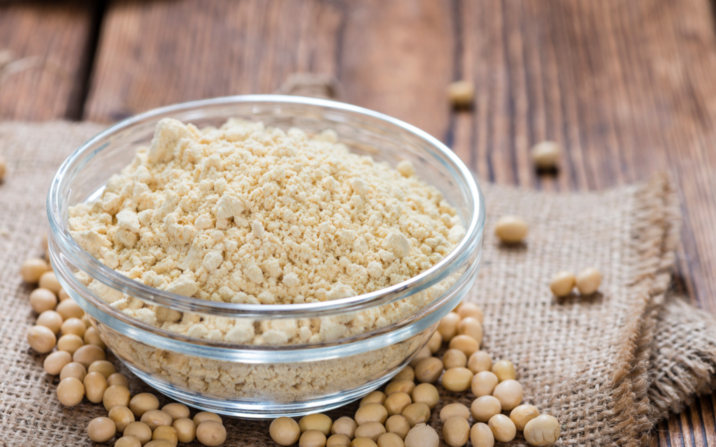 Soy flour on a wooden table, filling a bowl to the brim