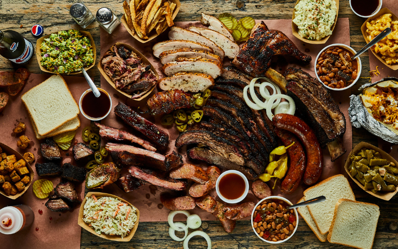 Different barbecue food assortments on a wooden table for National Barbecue Month