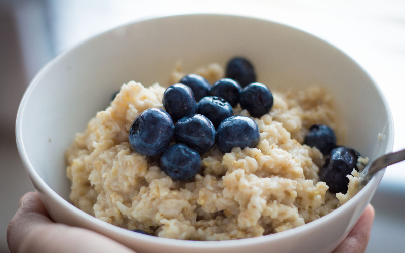 Bowl of oatmeal topped with blueberries in a white bowl to support digestive health